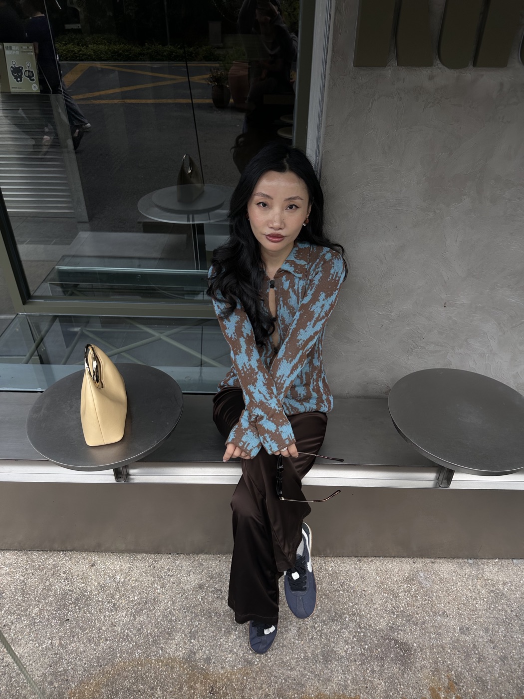 Wendy sitting outside a café in a blue and brown top