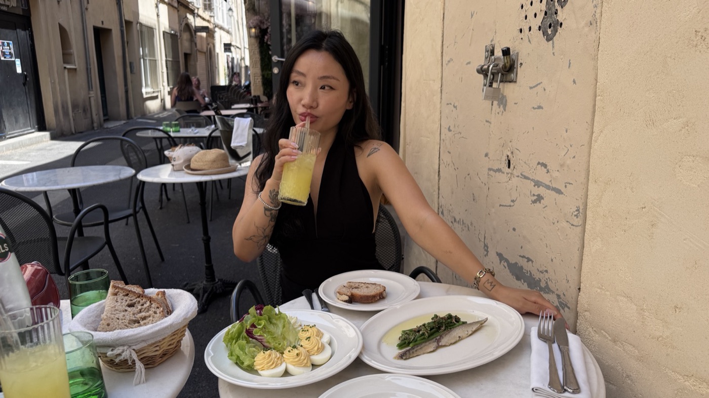 Wendy sipping a drink at a lunch table in France